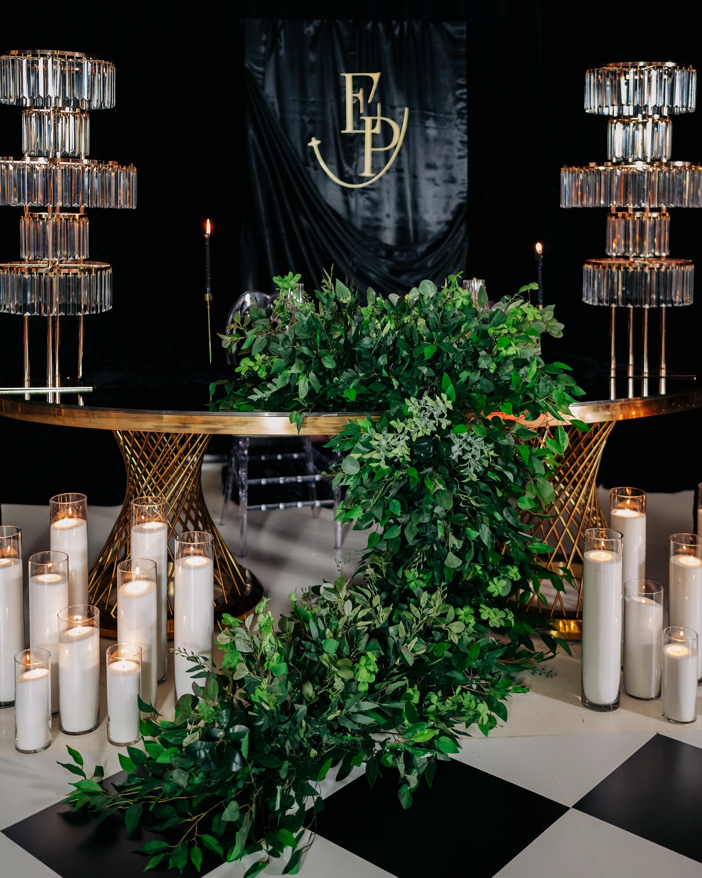 White floral installation with hanging crystal strands above a dramatic black-and-white anniversary setting.