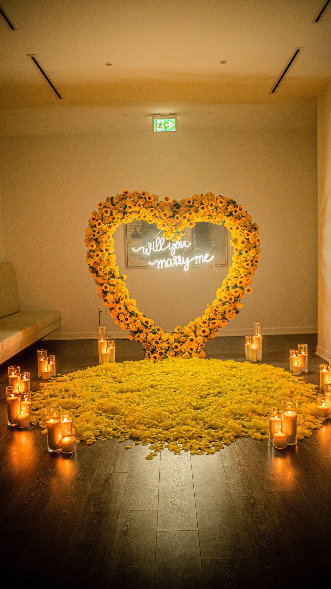 Heart-shaped sunflower and greenery arch surrounding an intimate proposal table with candles.